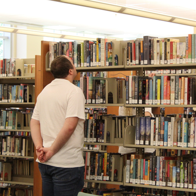 Man looking up at a stack of books at the library.