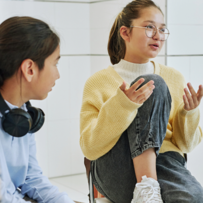 A teen talking to another teen in a group setting. 