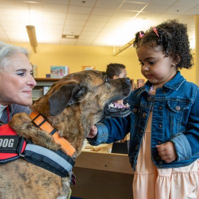 A woman with little girl petting a therapy dog. 