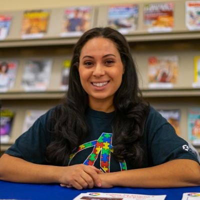 Smiling woman with magazines in the background.