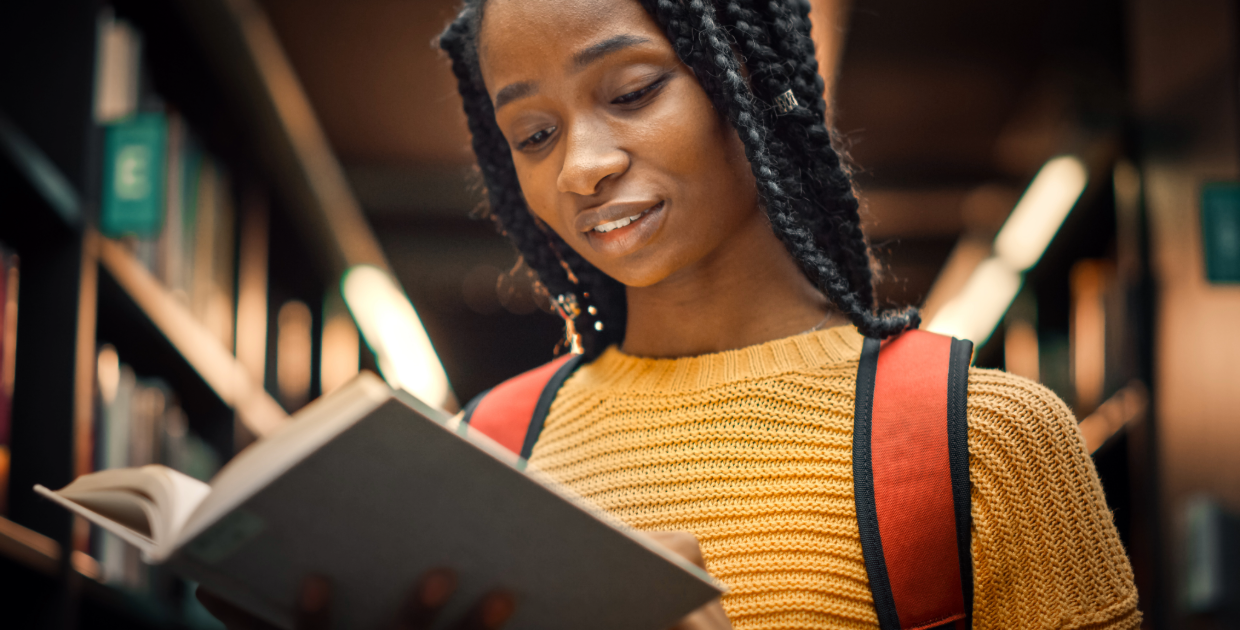 black teen reading a book in the library